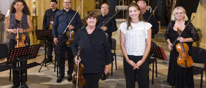 Musikwoche-Organisatorin Lore Schrettner mit Solistin Theresa Sayuri Brunner und der Louis Spohr Sinfonietta in der Pfarrkirche St. Marein