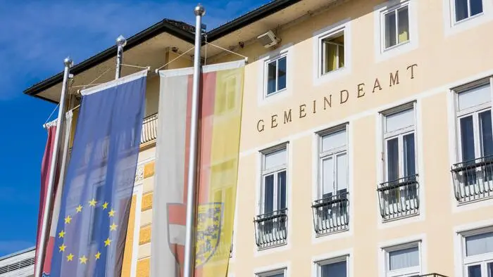 Ein gelbes Gebäude mit der Aufschrift „Gemeindearmt, davor die Kärnten und EU-Fahne