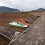 This photograph taken on January 15, 2024 shows an ancient pier and boats on dry soil next to the low water-level reservoir of Sau, with in background the Sant Roma de Sau church, in the province of Girona in Catalonia. Catalonia struggles with historic drought for three years, with some residents already experiencing water restrictions in their daily life. (Photo by LLUIS GENE / AFP)