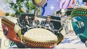 Foto zeigt drei junge Menschen in einem der Fahrgeschäfte