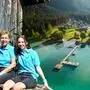 Eine Familie sitzt auf einem Steg, im Hintergrund ist eine Luftaufnahme des Weißensees