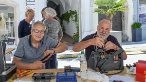 Zwei ältere Herren sitzen mit Werkzeug an einem Tisch 