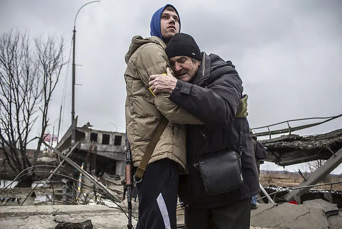 Nach russischem Artilleriefeuer muss ein Bewohner sein Haus in einem Vorort von Kiew verlassen. Er wird von einem ukrainischen Milizionär begleitet. 