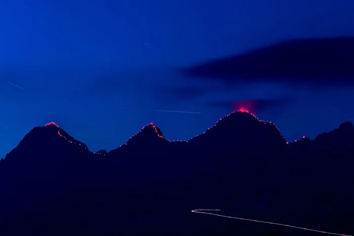 Das beleuchtete Dachstein-Dreigestirn. Die Lichtspuren im Vordergrund und am Himmel stammen von Flugzeugen. 