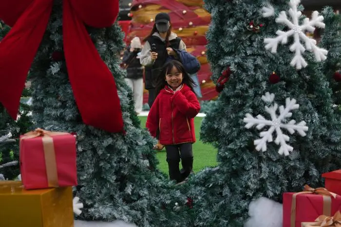 A child having fun near the Christmas decorations on display outside a shopping mall, in Beijing, Wednesday, Dec. 17, 2025. (AP Photo/Andy Wong)