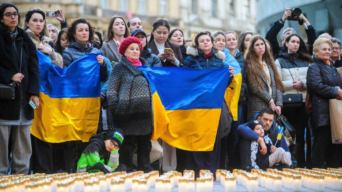 Menschen mit Ukraine-Flaggen vor einem „Lichtermeer“ aus Friedhofskerzen | Zehntausende Vertriebene leben aktuell in Österreich.