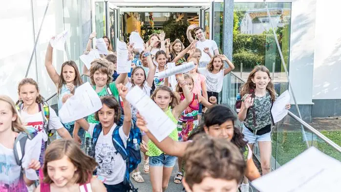 Schüler laufen mit ihren Zeugnissen aus einer Schule