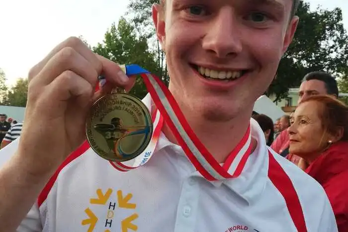 Stolz präsentiert er seine Goldmedaille.