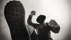 Victim's pov perspective, attacked on the street, being punched and mugged by aggressive violent man in hooded jacket on street, monochromatic black and white image.