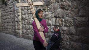 Eine orthodoxe Christin trägt ihr schlichtes Holzkreuz durch die Via Dolorosa in Jerusalem. Hier soll Jesus zur Hinrichtung geschleppt worden sein