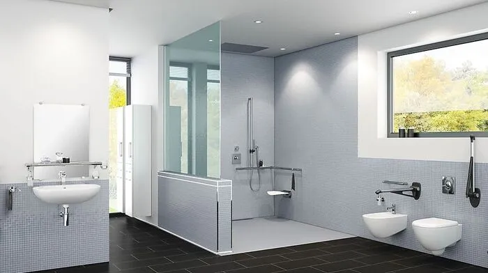 In barrierefreien Bädern muss nicht auf gutes Design verzichtet werden. In diesem Beispiel sind das unterfahrbare Waschbecken, das WC mit hochklappbaren Armstützen und die schwellenlose Dusche mit Sitz zu erkennen.