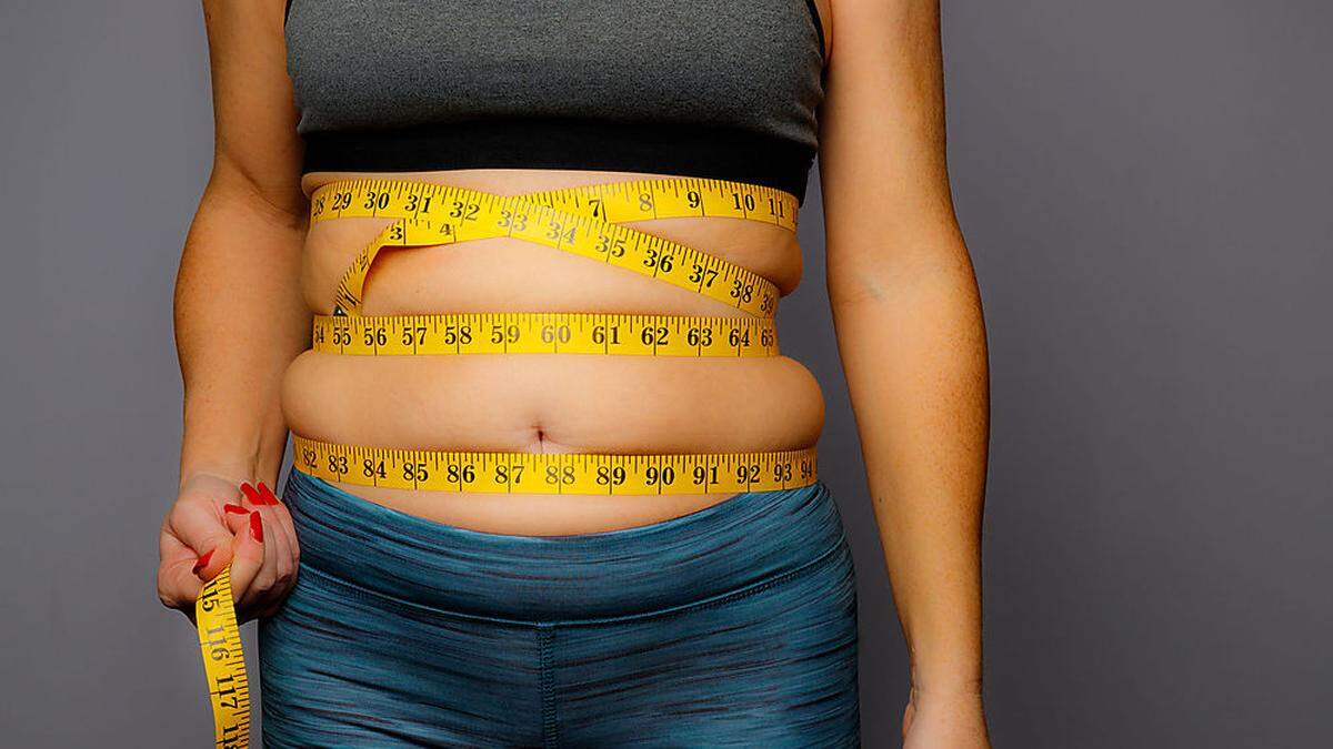 Woman in Active Wear With Squeezed Measuring Tape on a Gray Background