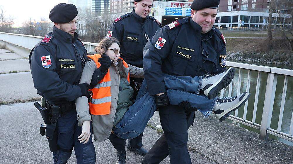 Klimaaktivistin Martha Krumpeck wird von Polizisten bei einer Aktion in Wien weggetragen