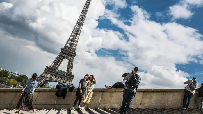 Menschen stehen auf einer Stiege, im Hintergrund ist der Eiffelturm.