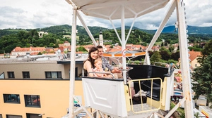 Ein Paar sitzt in einem Riesenrad und blickt über die Stadt Wolfsberg 