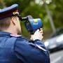 Symbolfoto: Polizist bei einer Geschwindigkeitskontrolle mit einem Radarmessgerät.