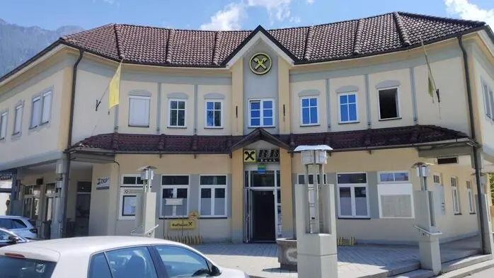 Blick auf eine Bankfiliale, davor steht ein weißes Auto