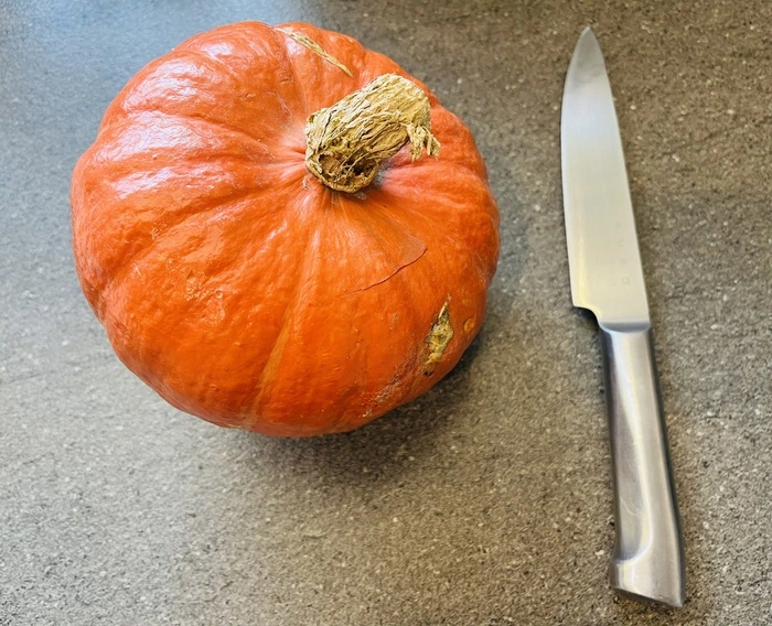 Mit einem scharfen Messer und etwas Kraft lässt sich der Kürbis gut köpfen - anfangs eher stechen als schneiden