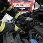 Feuerwehrmann greift nach schwarzer Katze im Motorraum eines Autos