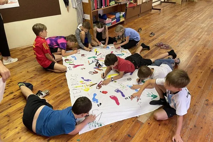 Die Kinder bemalen ein Transparent, das im Sommer die Schul-Fassade zieren wird
