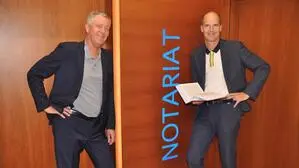 Zwei Männer stehen vor einer Tür mit der Aufschrift „Notariat“