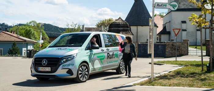 Ein Taxi an einer Haltestelle. Ein Mensch steht davor.