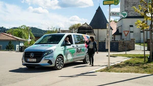 Ein Taxi an einer Haltestelle. Ein Mensch steht davor.