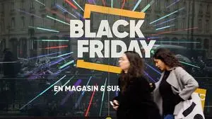 (FILES) In this file photo taken on November 23, 2018 pedestrians walk past a store window with a sign announcing the so-called "Black Friday" sales, in Paris. (Photo by STRINGER / AFP)