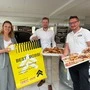 Eine Frauen und zwei Männer lachen in die Kamera