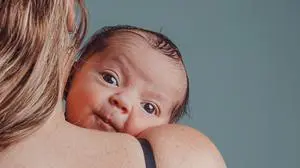 Mother holds her newborn son with surprised expression