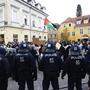 Foto zeigt Polizisten in Sicherheitsausrüstung von hinten und Demonstranten | Teilnehmer und Polizisten der angekündigten, aber behördlich untersagten, Pro-Palästina Demonstration am Freitag in Graz