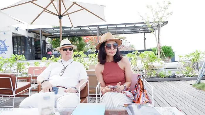 Ein Mann und eine Frau, beide tragen Hüte, sitzen auf einer Terrasse