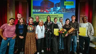 Mehrere Menschen stehen gemeinsam auf einer kleinen Bühne