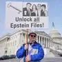 Gary Rush, College Park, MD, holds a sign before a news conference on the Epstein files in front of the Capitol, Tuesday, Nov. 18, 2025, in Washington. (AP Photo/Mariam Zuhaib)