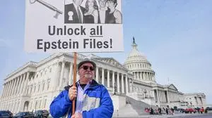 Gary Rush, College Park, MD, holds a sign before a news conference on the Epstein files in front of the Capitol, Tuesday, Nov. 18, 2025, in Washington. (AP Photo/Mariam Zuhaib)