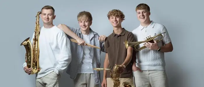 Vier junge Männer mit ihren Instrumenten lachen in die Kamera