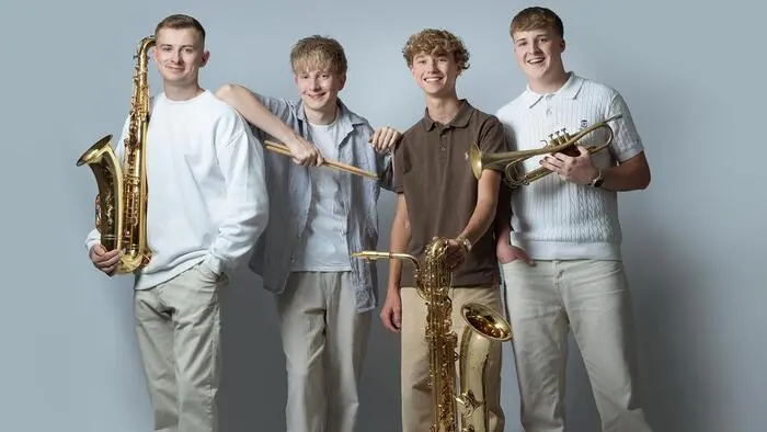 Vier junge Männer mit ihren Instrumenten lachen in die Kamera