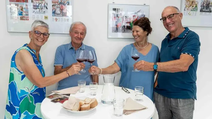 Vier Personen stehen um einen Tisch und stoßen an