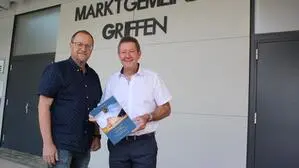 Zwei Männer stehen vor dem Gemeindeamt mit der Aufschrift „Griffen“
