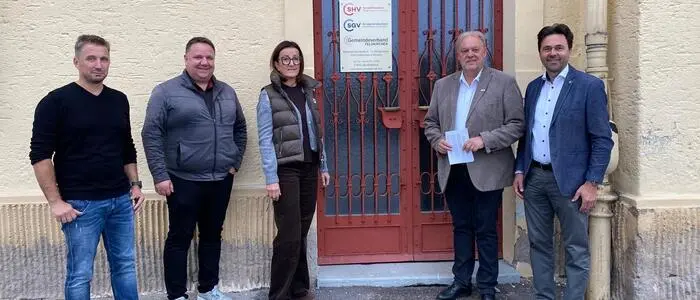 Fünf Politiker stehen vor einer Wand und einer Tür.