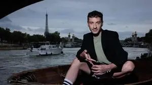 TOPSHOT - French Artistic Director for the Opening and Closing Ceremonies of the Paris 2024 Olympic and Paralympic Games Thomas Jolly, poses near the Seine River with the Eiffel tower in the background (L) in Paris on July 2, 2024. (Photo by JOEL SAGET / AFP)