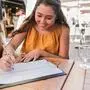 Happy young woman fills out contact person list in a restaurant - Coronavirus lifestyle