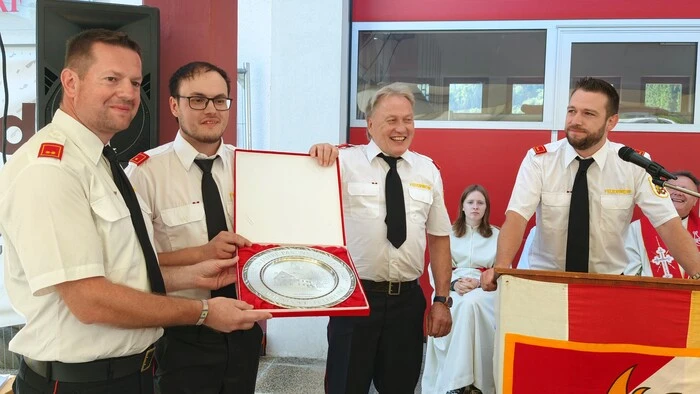 Vier Feuerwehrmänner halten eine Auszeichnung in der Hand
