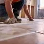 A technician laying floor tiles in a renovated house