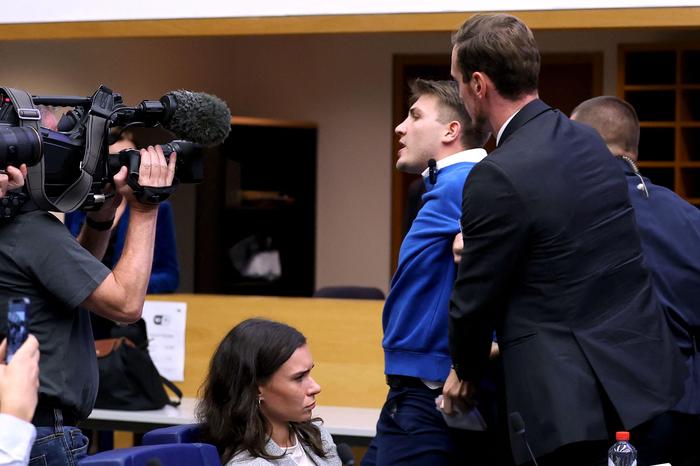 Ein Aktivist wird während der Pressekonferenz aus dem Saal geführt