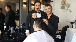 Zwei Männer in schwarzer Kleidung schneiden einem Herren die Haare | Geschäftsführer Hakki Orhan aus Wolfsberg mit Mitarbeiter Ahmet Baran (von links)