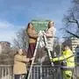 Die vier Personen stehen auf einer Leiter vor dem neuen Schild der Alfred-Stingl-Brücke