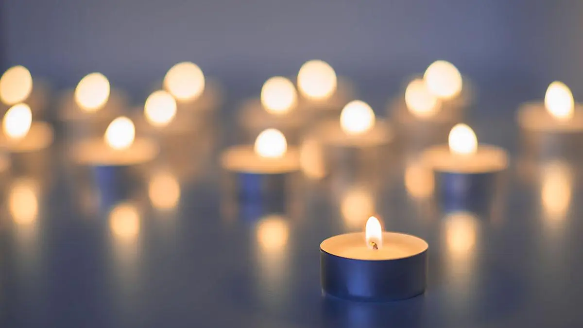 Flame of many candles burning on the background in blue and yellow color