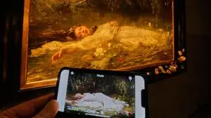 The opening part of Taylor Swift's video "The Fate of Ophelia" is displayed on a mobile phone in a museum showing a painting by Art Nouveau painter Friedrich Heyser showing Ophelia, a Shakespeare Character, in Wiesbaden, Germany, Thursday, Oct. 16, 2025. (AP Photo/Michael Probst)