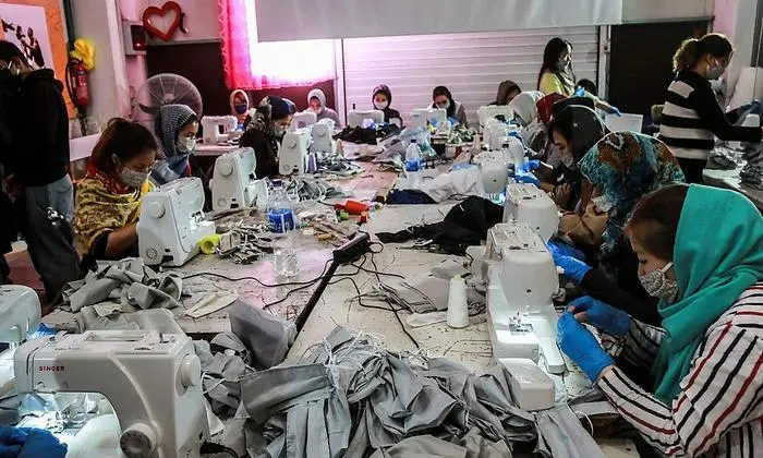Migrants from the Moria camp sew handmade protective face masks at the premises of the NGO 